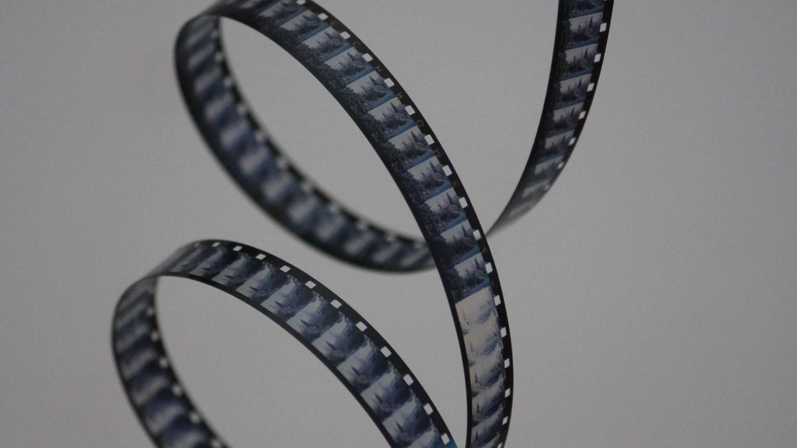 회색 배경 앞에서 나선형으로 말린 35mm 필름 조각