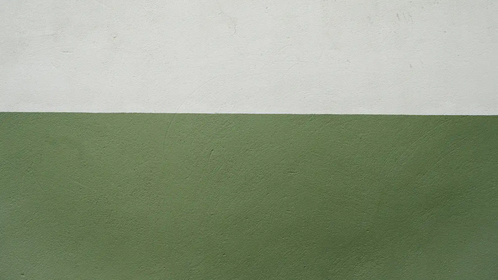 흰 벽과 연한 세이지색 벽이 가로로 맞닿은 미니멀한 벽면